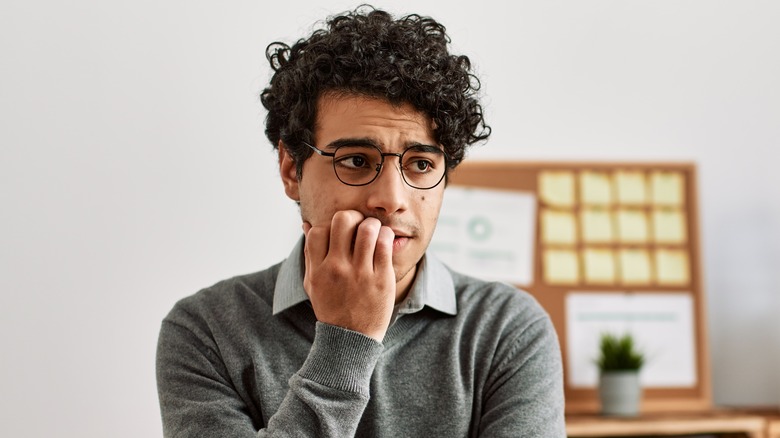 Young man biting fingernails