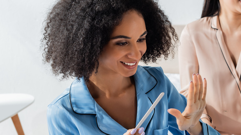 Smiling woman filing fingernails