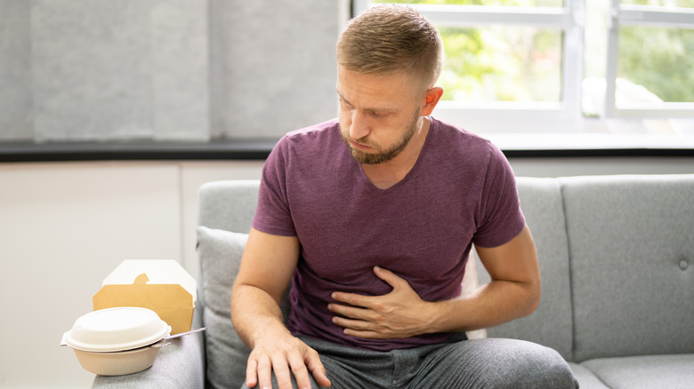 man holding his stomach next to fast food