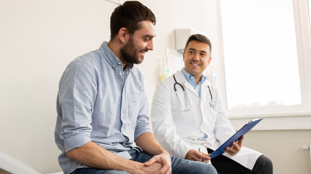 young man with smiling doctor looking at clipboard