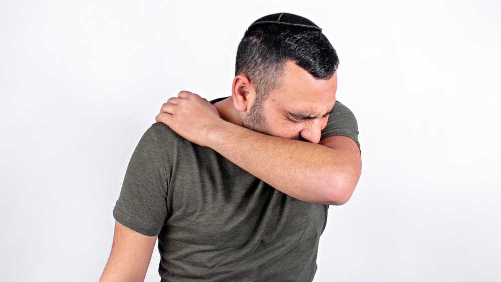 man coughing into arm