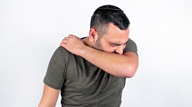 man coughing into arm