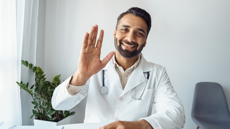 A doctor greeting a patient through a screen