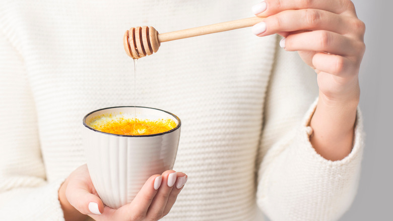 woman adding honey to drink