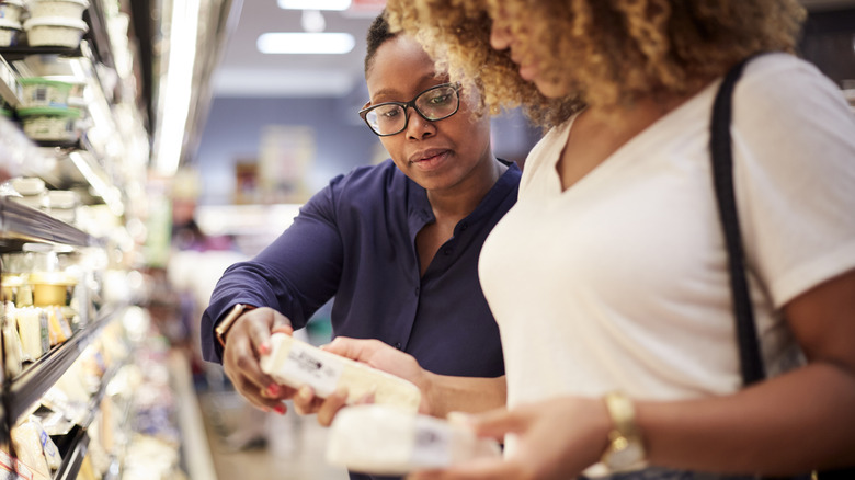 two women looking at nutrition labels of cheese