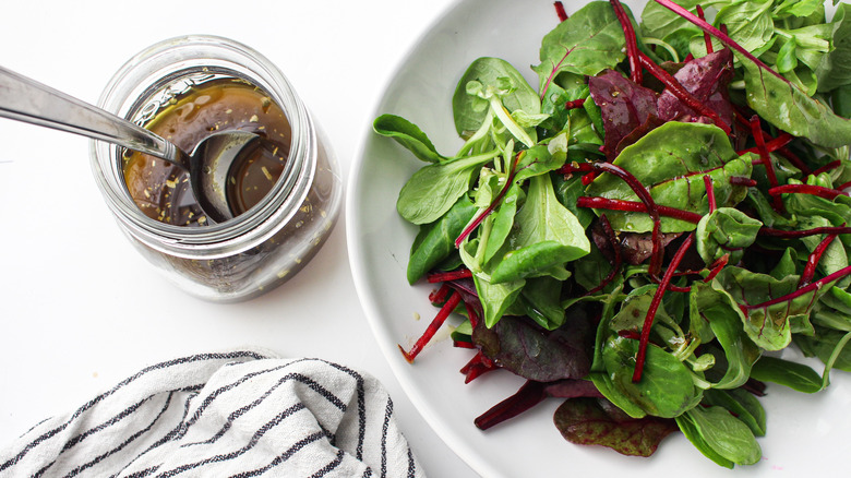 a jar of dressing and salad greens