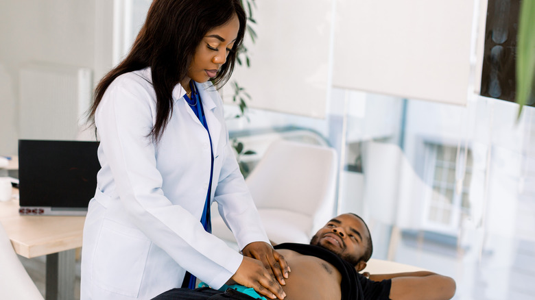 doctor pressing on patient's abdomen
