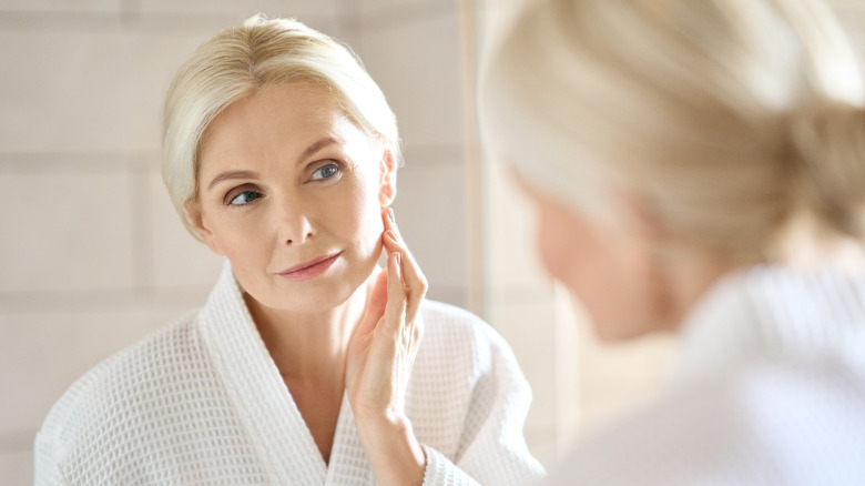 Older woman examining skin in mirror