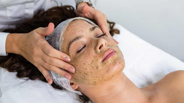 Hands exfoliating woman's face