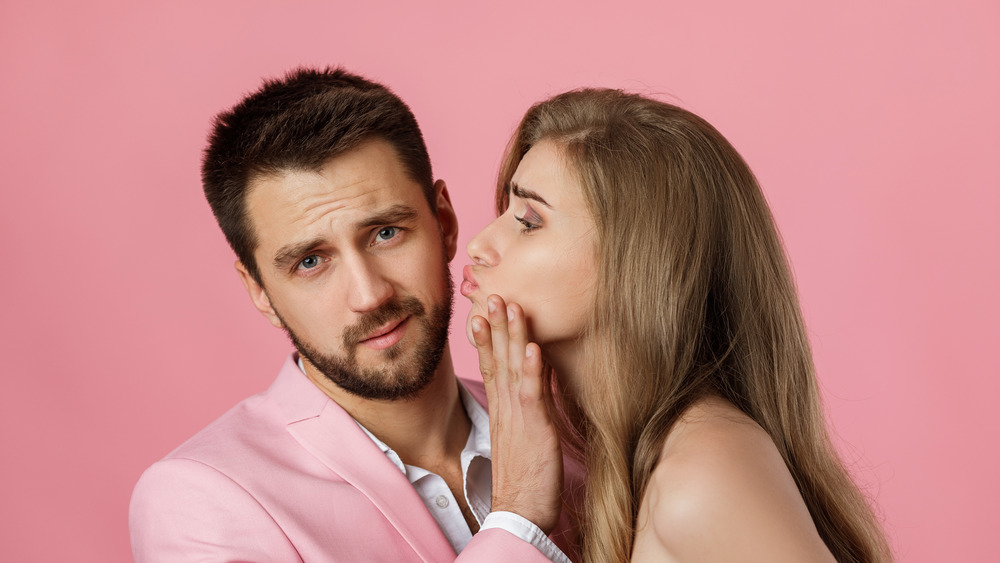 Man stopping woman from kissing him