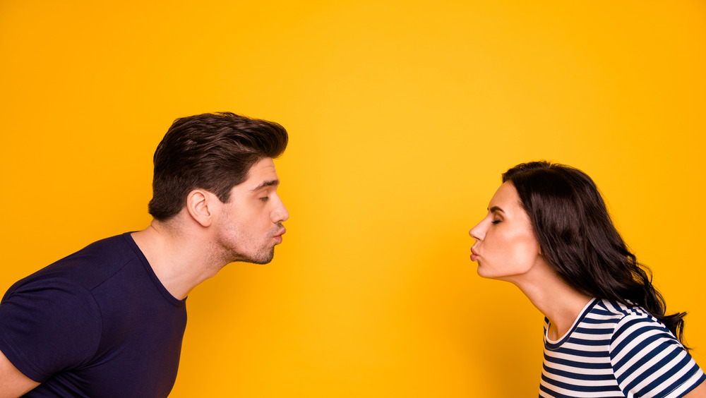 Couple on yellow background kissing far apart