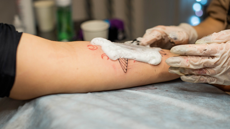 Close up of tattoo artist washing tattoo site after procedure