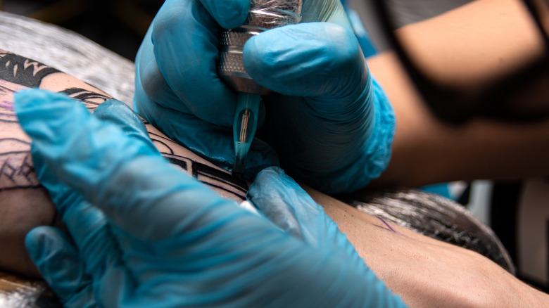 Close up of tattoo artist with gloved hands tattooing customer