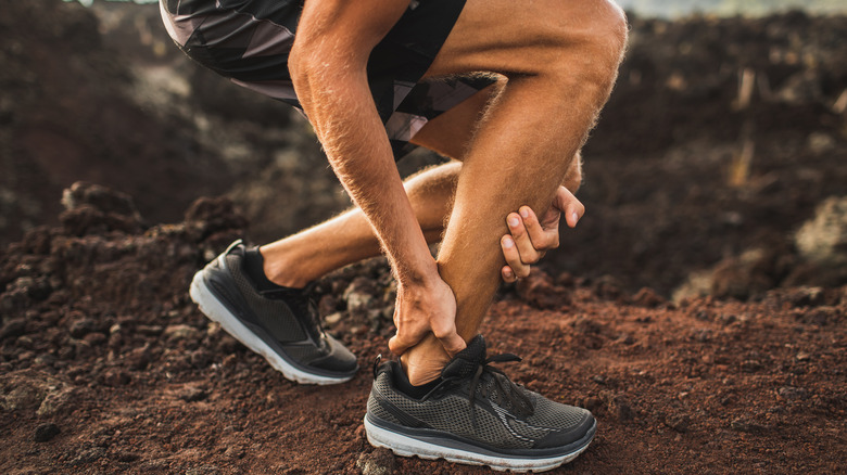 man grabbing Achilles tendon