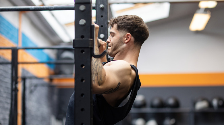 A muscular man doing pull-ups at the gym