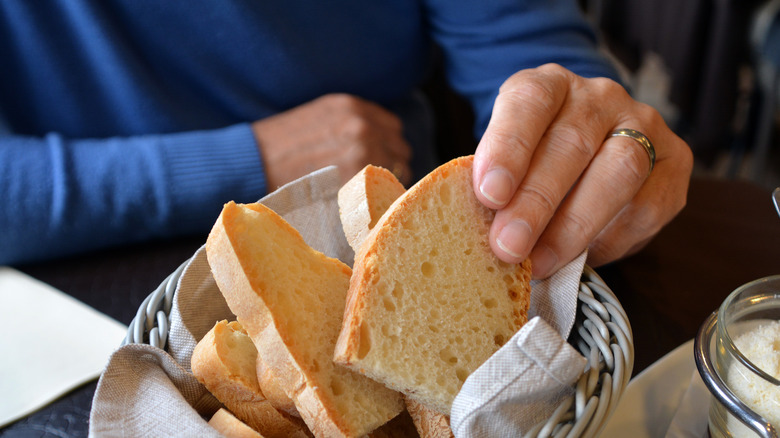 man's hand reaching into a basket of bread