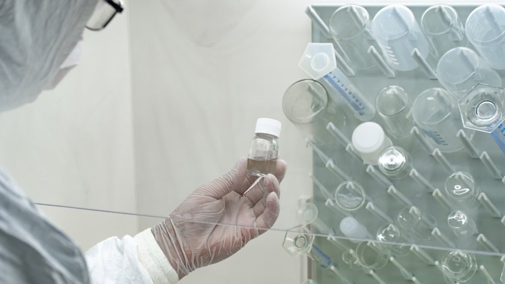 Research scientist holding small bottle of clear fluid