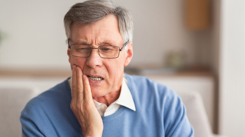 Older man holding jaw in pain