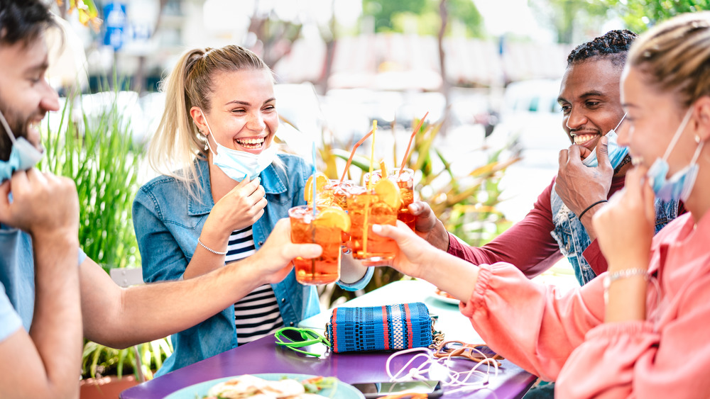 People with facemasks toasting drinks