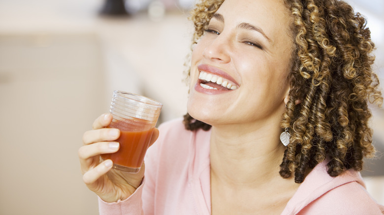 smiling woman holding glass of V8