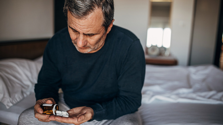 A man looking at pill capsules 