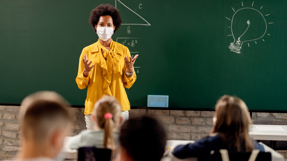 Masked teacher at a chalkboard