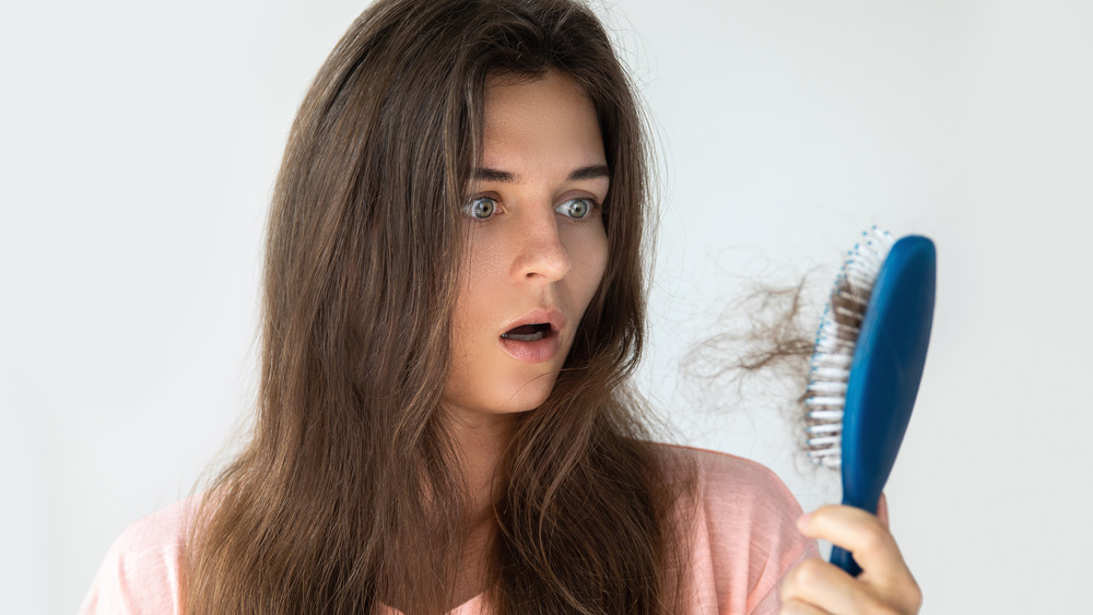 Young woman surprised by brush with excessive hair in it