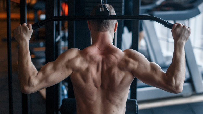 Athletic man doing behind-the-neck lat pulldowns