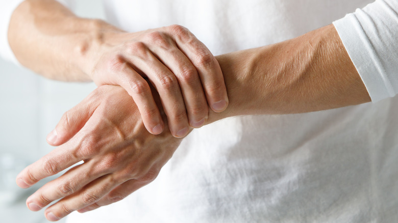 A woman rubbing her wrist and grimacing