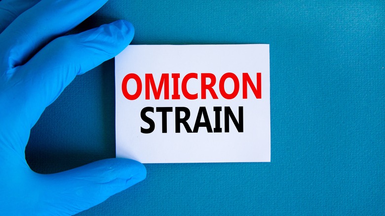 New covid-19 omicron variant strain symbol. Hand in blue glove with white card. Concept words Omicron strain. Medical and COVID-19 omicron variant strain concept.