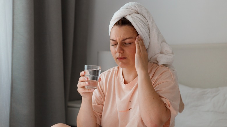 Wincing woman touching head in pain