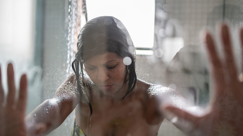 Woman holding on to glass shower door