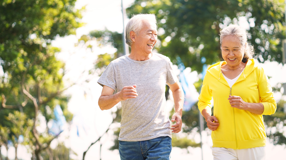 Older Asian couple jogs or walks briskly outdoors