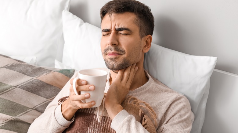Wincing man holding tea mug