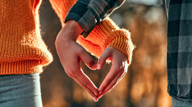 two people with their hands making heart shape