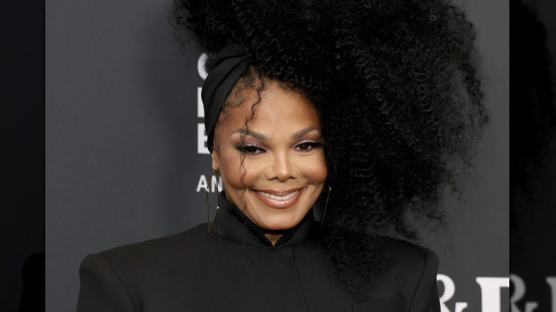 Janet Jackson smiling at a celebrity event wearing a black outfit