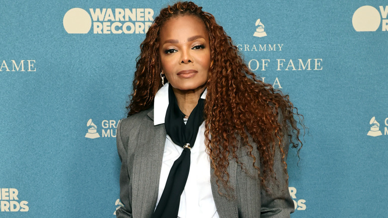 Janet Jackson smiling at a celebrity event wearing a black outfit