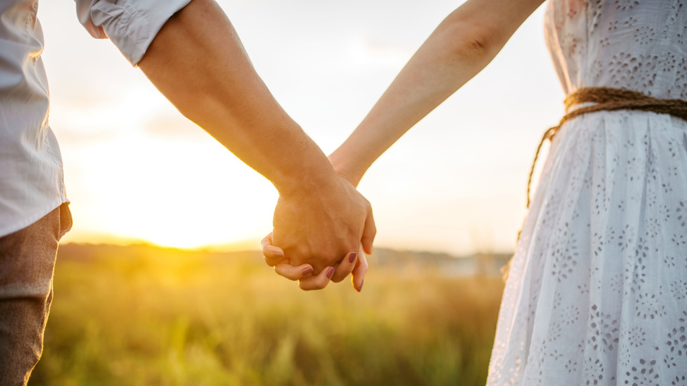 Couple holds hands at sunset