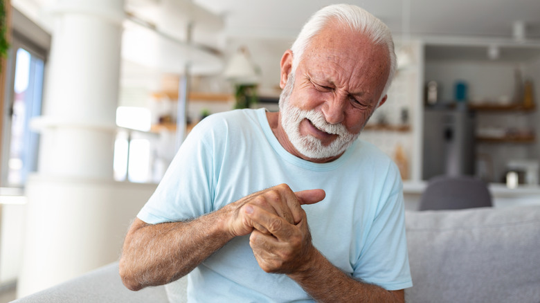 man grimacing in pain holding injured fingers