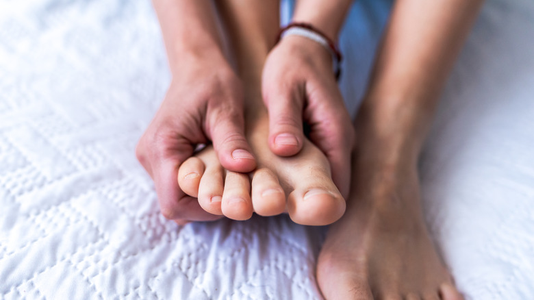 person holding foot and looking at toenails