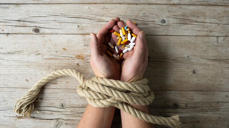 hands bound holding pills 