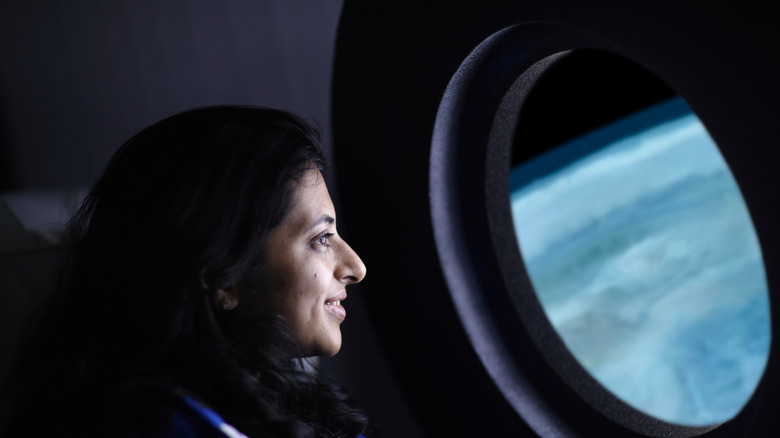 astronaut looking out window at Earth
