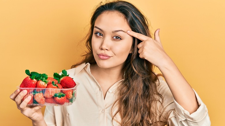 woman holds strawberries points to brain