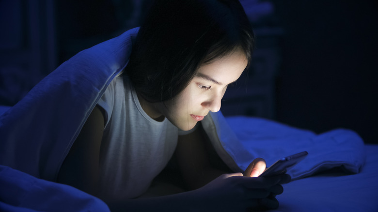 Teen in bed on smartphone at night