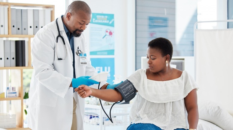 African American doctor taking patient blood pressure