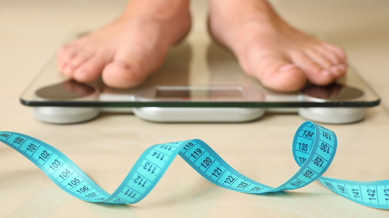 measurement tape in front of someone on a scale