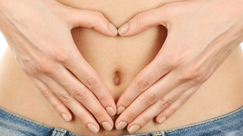 Woman making the heart sign with her hands around the belly button