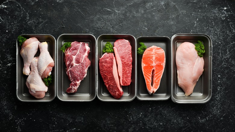 raw chicken, beef, and fish on trays