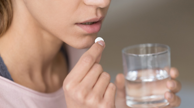 close-up of a woman taking a pill with water