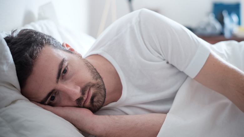 A depressed man laying in bed